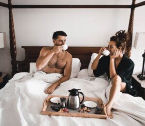 Couple sharing a romantic breakfast in bed representing the application of skills learned in online Premarital Counseling in San Antonio, TX. Build a strong future for your relationship today.