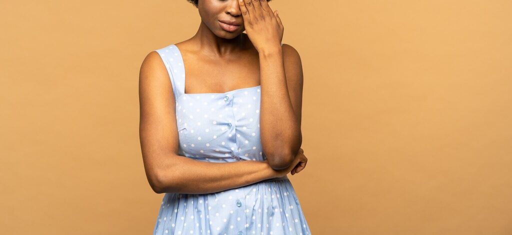 African American woman standing with her arms crossed in obvious distress representing someone overcome by past trauma who would benefit from online trauma therapy in Austin, TX.