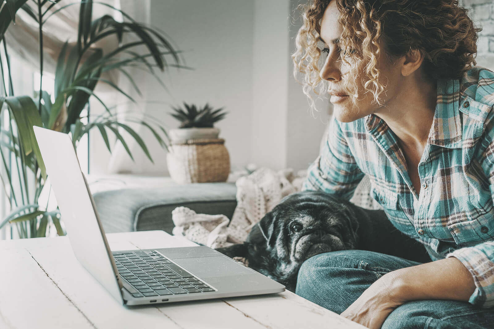 Woman working on her laptop with her pug dog by her side, representing the ease of accessing Online Trauma Therapy in Austin, TX.