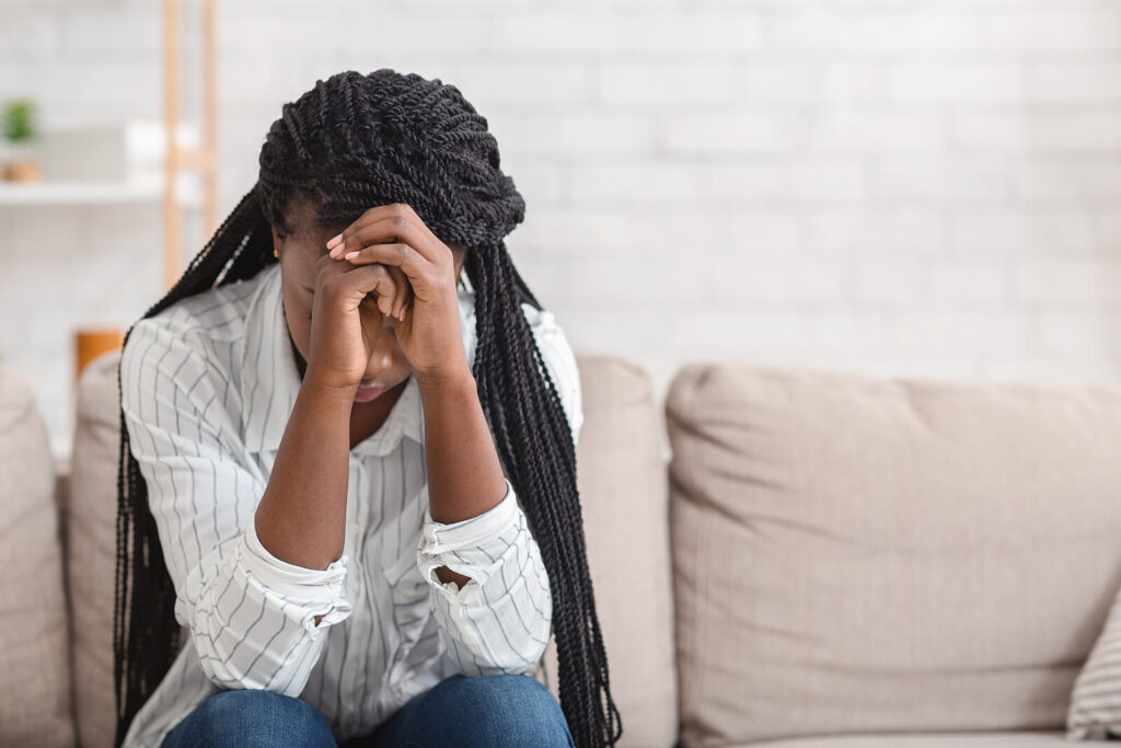 Woman with her head in her hands looking at the floor representing someone who is struggling with anxiety and would benefit from Online Therapy for Anxiety in San Antonio, TX. 