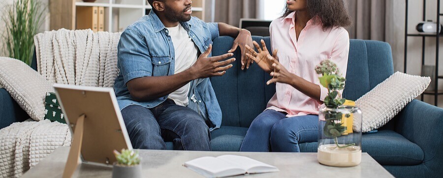 African American couple sitting on their couch talking to each other representing the improved communication that can come through Trauma Therapy in San Antonio, TX.