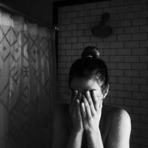 Woman feeling her emotions, looks to also be very emotional and stressed, could be getting her alone time in her shower. San Antonio Modern Wellness Counseling, Virtual Counseling. 78230, 78255, 78217, 78256, 78258. 