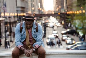 Man going through a hard time and feeling all his emotions, taking a second to sit down while so much is going on behind him. Taking a breather in the city. San Antonio, Tx. Modern Wellness Counseling. 78255,78258,78230,78249.